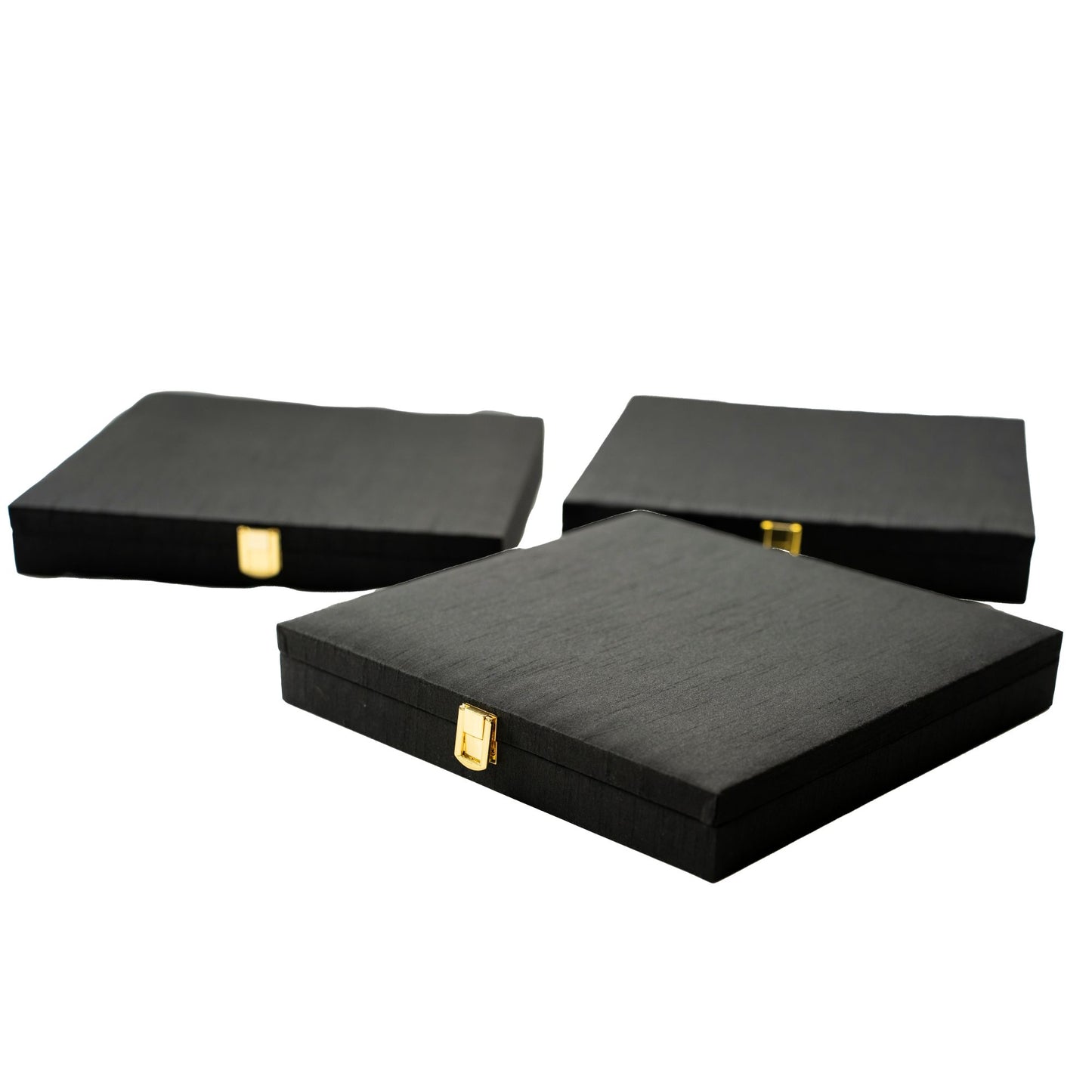 Three black jewelry boxes with gold clasps on a white background