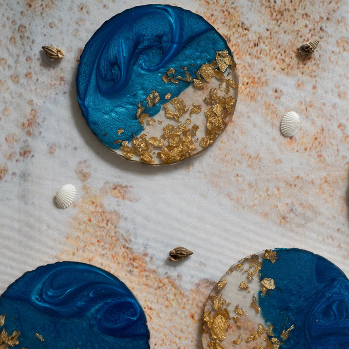 Decorative circular items with blue and gold design on a textured surface