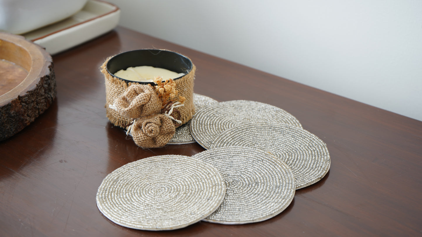 Set of round woven coasters on a wooden surface with a candle and decorative elements.