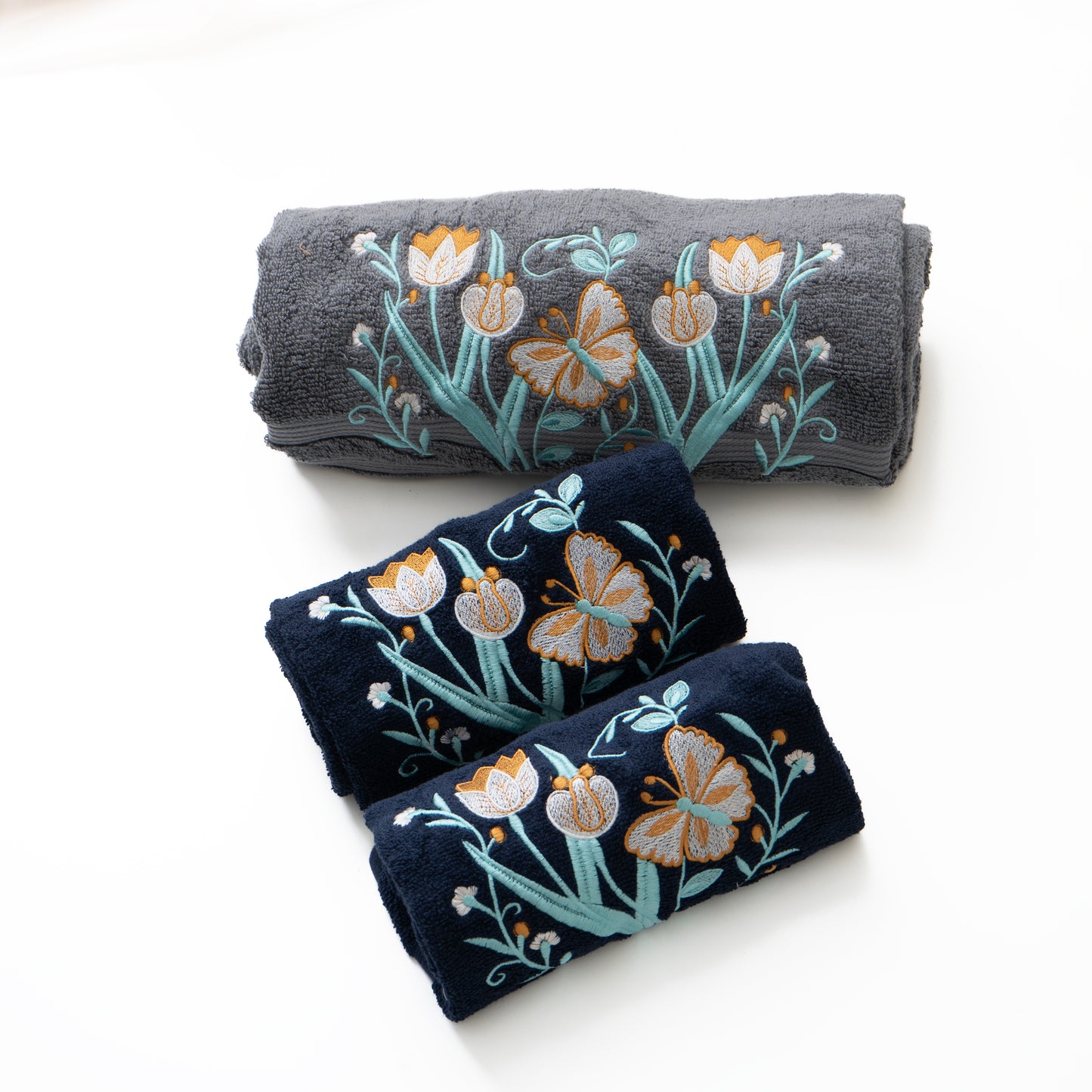 Three folded towels with floral embroidery on a white background