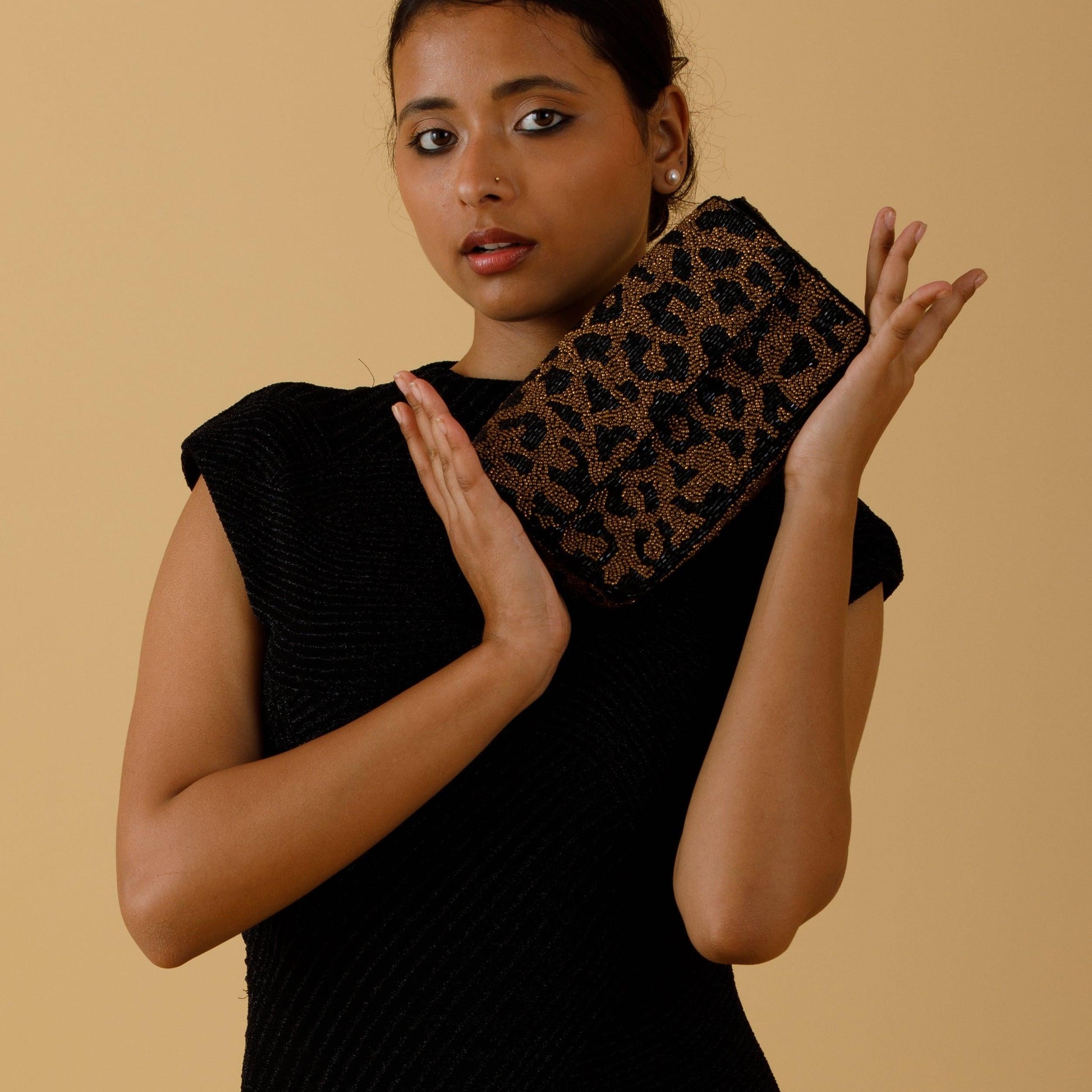 Woman holding a leopard print clutch against a beige background