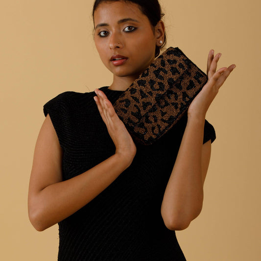 Woman holding a leopard print clutch against a beige background