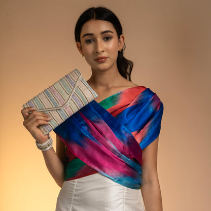Woman holding a colorful striped clutch against a beige background