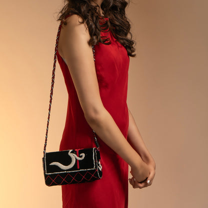 Woman in a red dress holding a black handbag with white design on a beige background