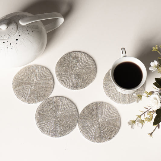 Set of round woven coasters on a table with a teapot and cup.