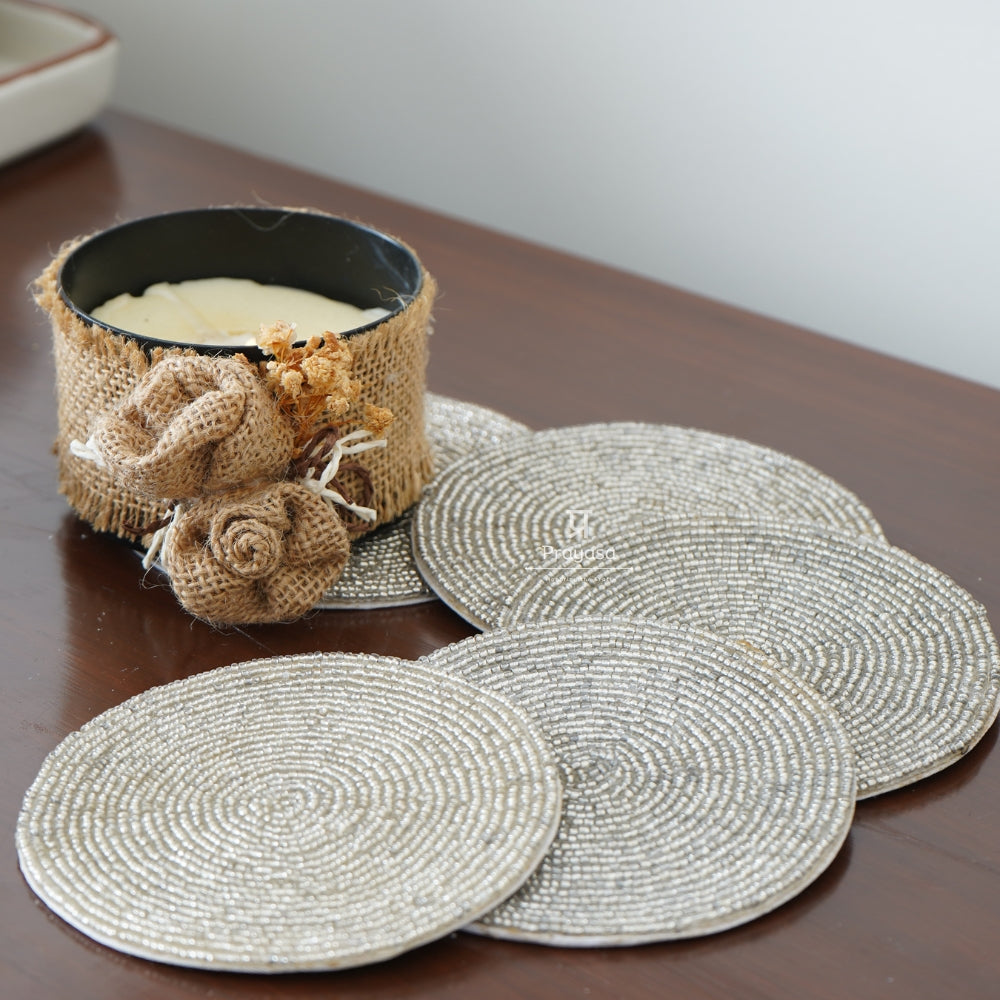 Set of round woven coasters on a wooden surface with a decorative candle.