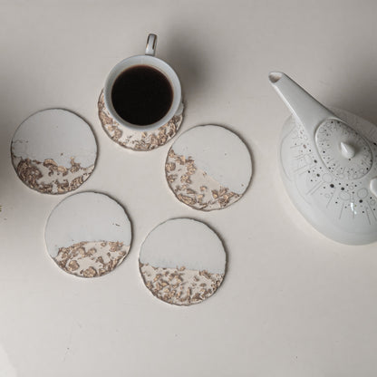 Set of ceramic coasters with a teapot and cup on a light surface
