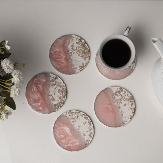 Set of pink and white marbled coasters with a cup of coffee and teapot on a light surface.