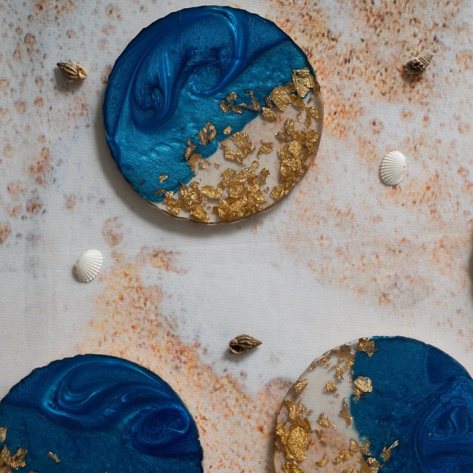 Decorative circular items with blue and gold design on a textured surface