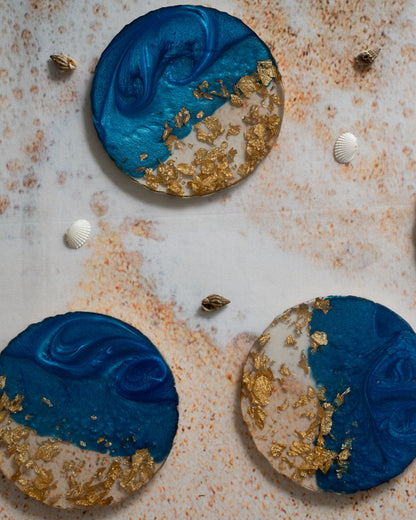 Decorative circular items with blue and gold design on a textured surface