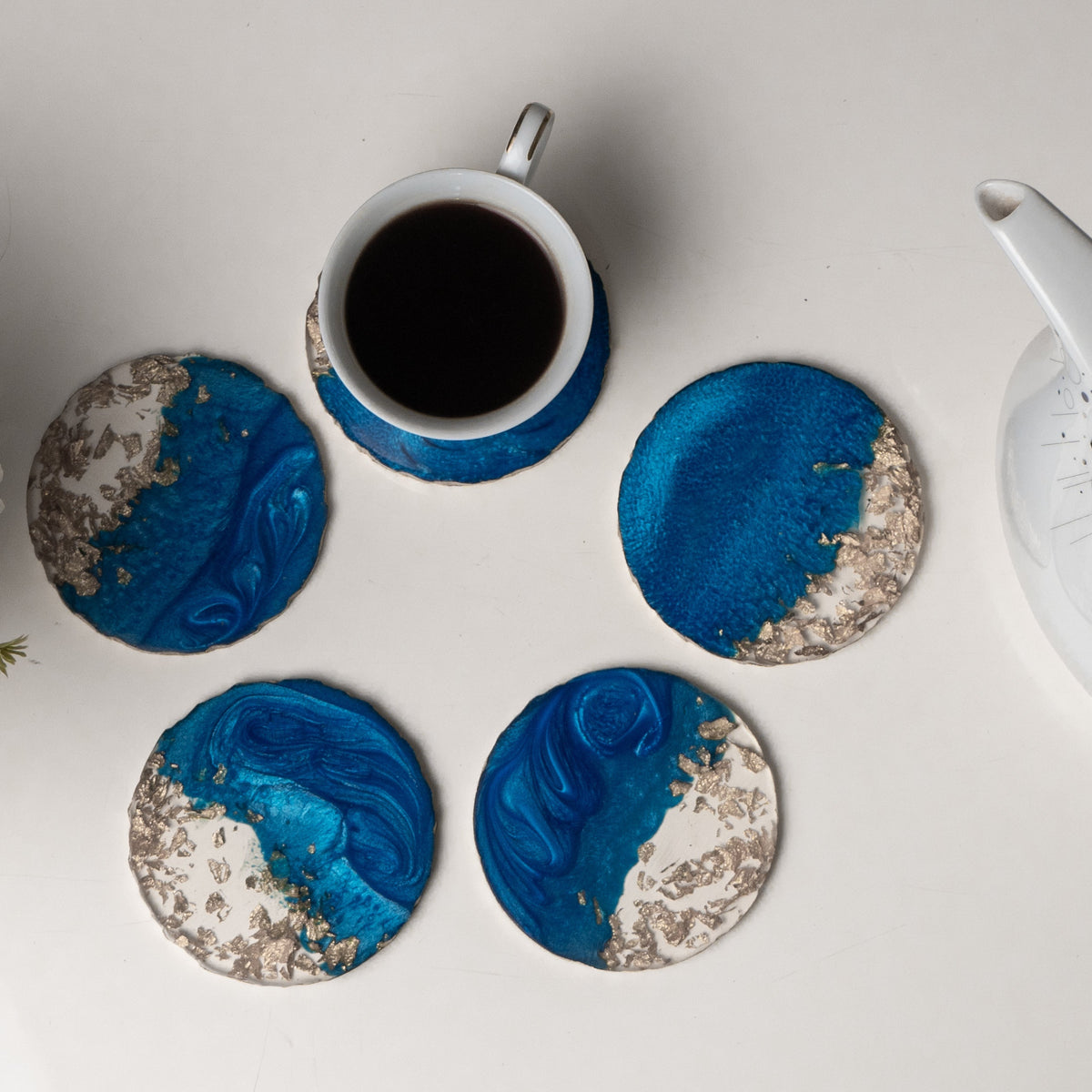 Blue and white marbled coasters with a cup of coffee on a light surface.