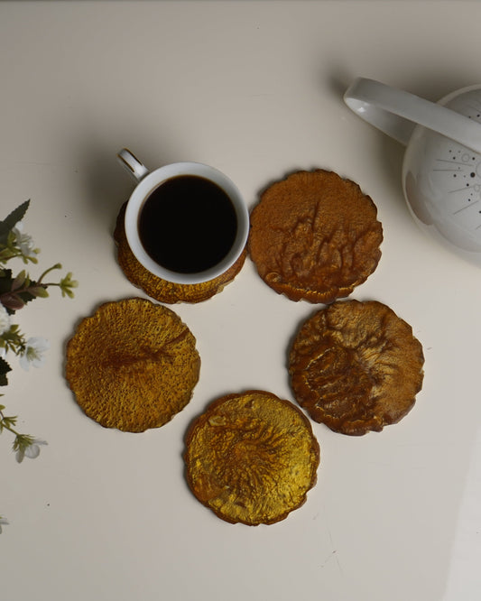 Cookies and a cup of coffee on a white surface with a teapot and flowers.