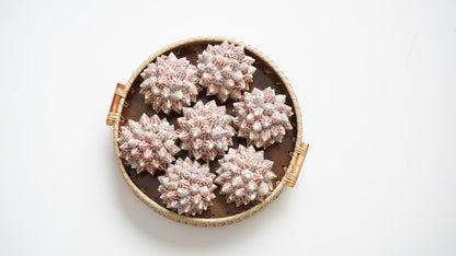 Decorative round basket with pink spherical objects on a white background