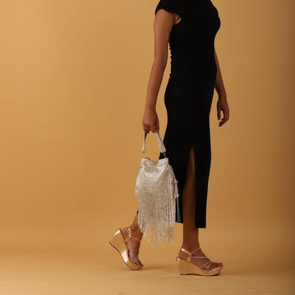 Woman holding a silver clutch against a beige background