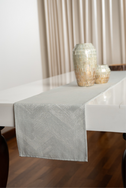 Table with a gray textured table runner and decorative vases against a neutral background