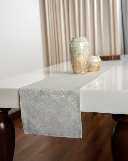 Gray table runner on a white marble table with decorative vases.