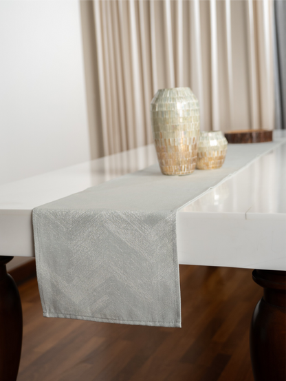 Light gray table runner on a white table with decorative vases against a neutral background