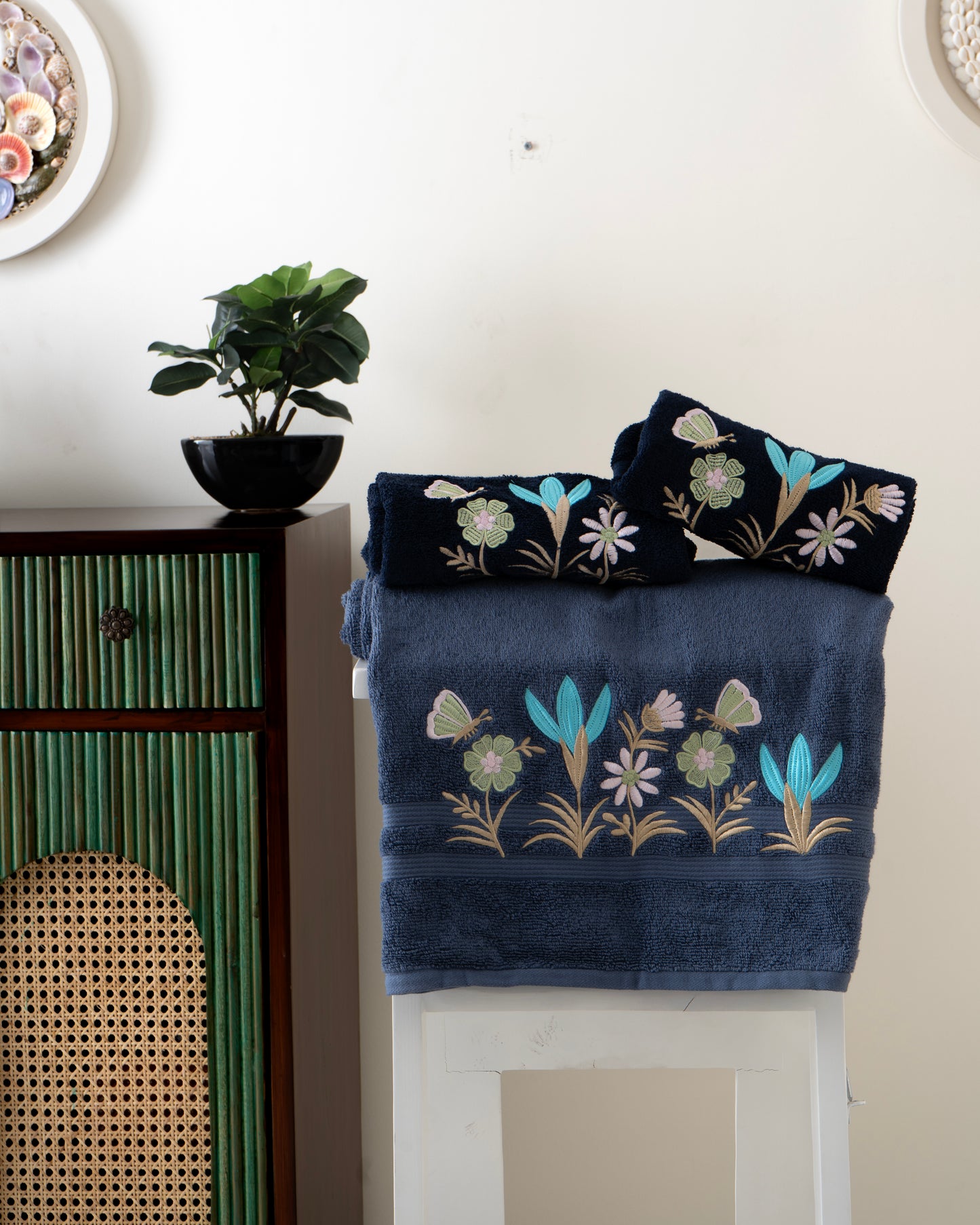 Set of embroidered towels on a cabinet with a plant in the background